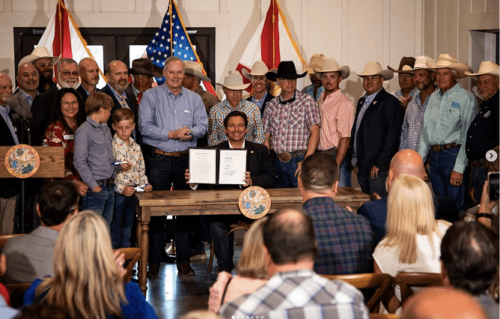 A press photography shoot of a piece of legislation being passed. There is an American flag in the background.
