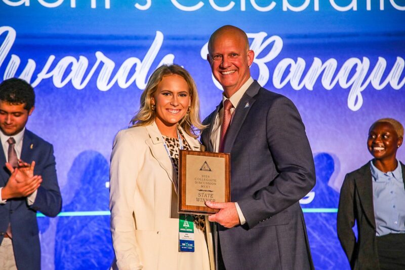 Jaley Moseley, UF student and collegiate discussion meet winner, poses on stage with FFBF President Jeb S. Smith.