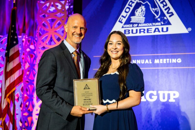 Emma Smith, Warner University student and collegiate discussion meet winner, poses on stage with FFBF President Jeb S. Smith.