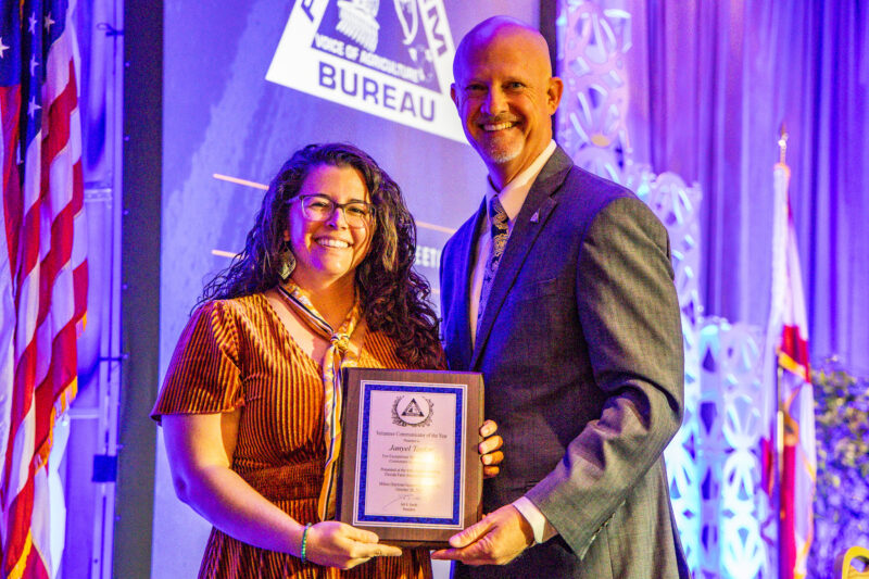 Two people holding an award plaque on a stage during the 2025 Florida Farm Bureau annual meeting